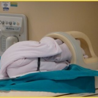 Il neonatino, coperto e monitorato sta per entrare nel magnete della Risonanza Magnetica mentre la sua testolina è già nella bobina.